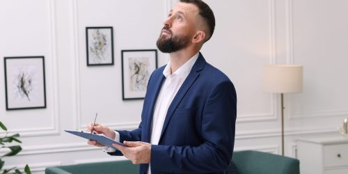 Real estate appraisal. Inspector with clipboard conducting property valuation indoors